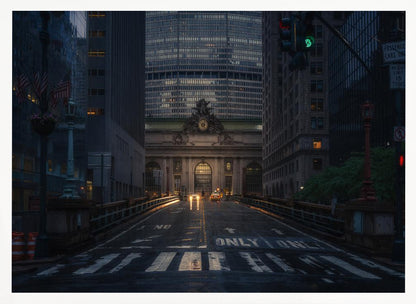 A moody photograph of a wet city street at dusk, leading towards the illuminated facade of Grand Central Terminal in New York City, which is framed by tall, modern skyscrapers. Decor