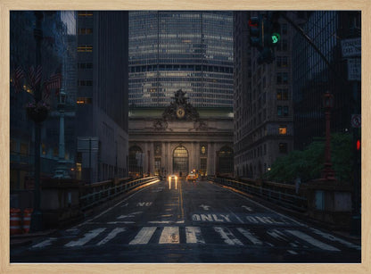 A moody photograph of a wet city street at dusk, leading towards the illuminated facade of Grand Central Terminal in New York City, which is framed by tall, modern skyscrapers. Decor
