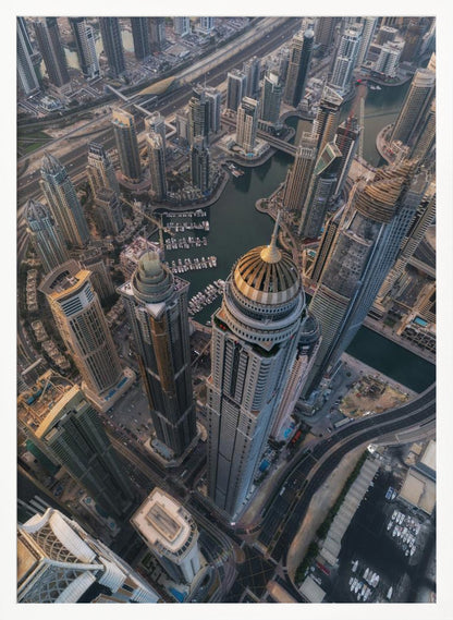 An aerial, bird's-eye view of the dense Dubai Marina, with towering skyscrapers casting long shadows. A waterway snakes through the urban canyon, with numerous yachts docked in the marina. A prominent skyscraper with a distinctive golden dome stands in the foreground. Artwork
