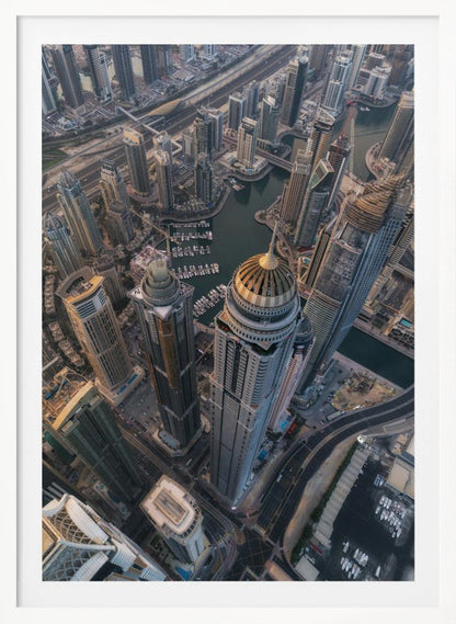 An aerial, bird's-eye view of the dense Dubai Marina, with towering skyscrapers casting long shadows. A waterway snakes through the urban canyon, with numerous yachts docked in the marina. A prominent skyscraper with a distinctive golden dome stands in the foreground. Artwork