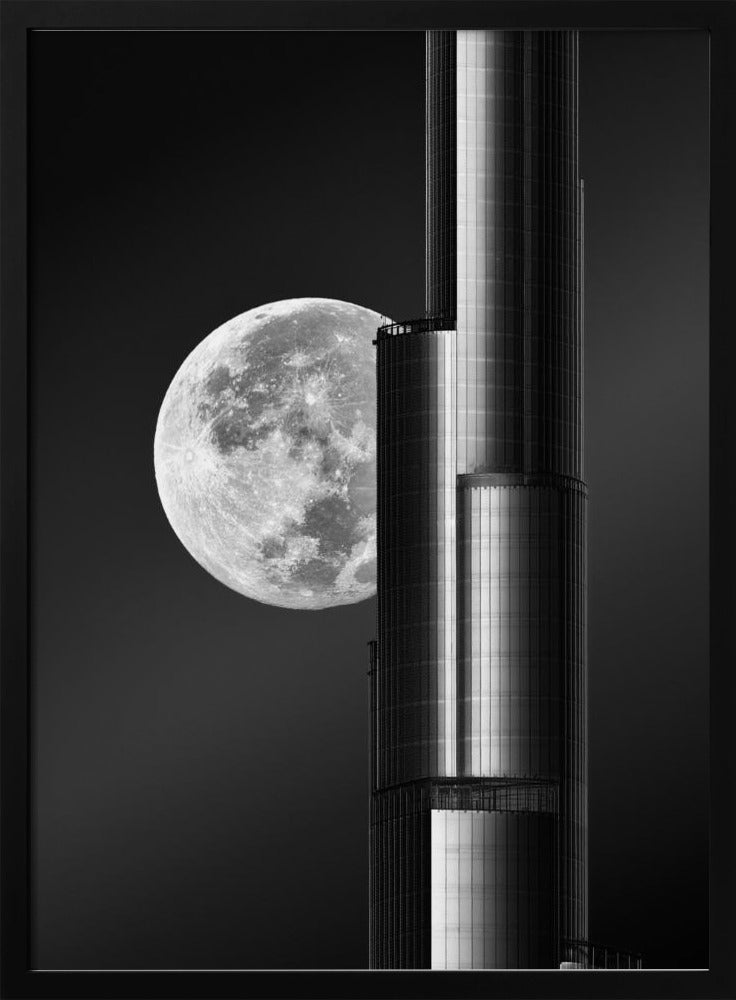 A dramatic black and white photograph of a massive full moon positioned next to a modern, towering skyscraper. The high-contrast image creates a striking juxtaposition between the natural celestial body and the man-made architectural marvel against a dark night sky. Poster