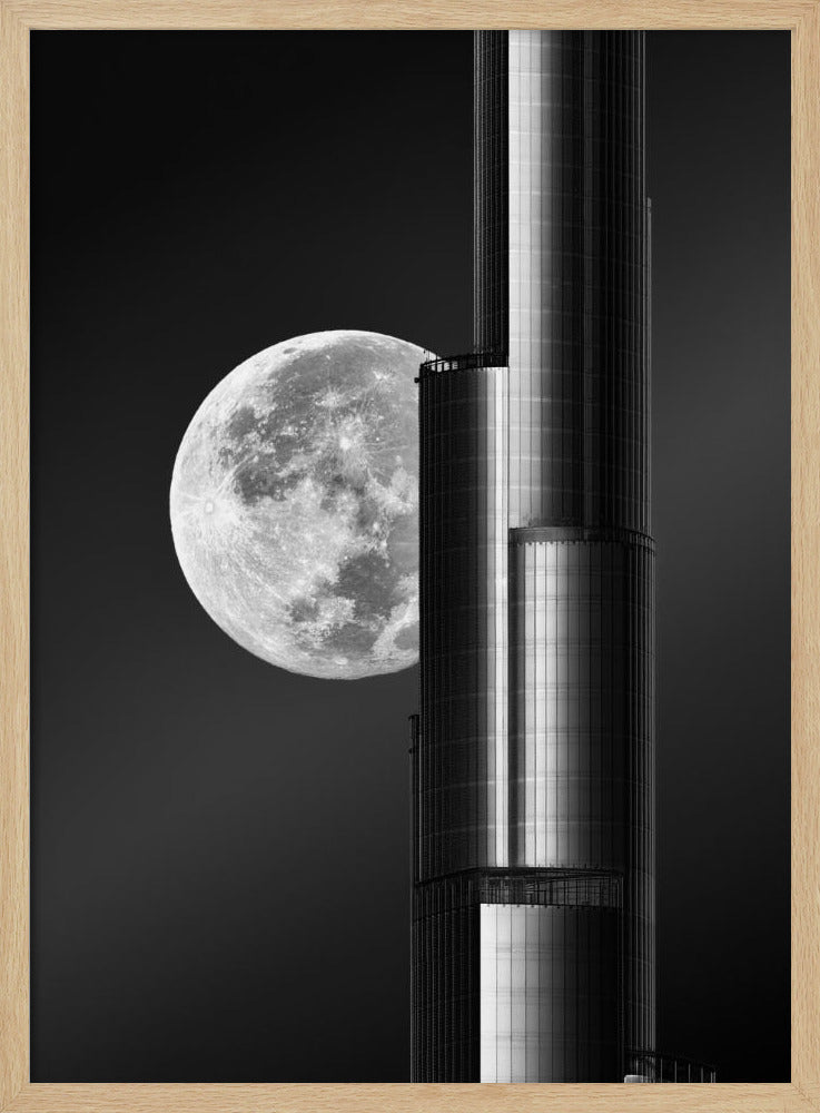 A dramatic black and white photograph of a massive full moon positioned next to a modern, towering skyscraper. The high-contrast image creates a striking juxtaposition between the natural celestial body and the man-made architectural marvel against a dark night sky. Poster