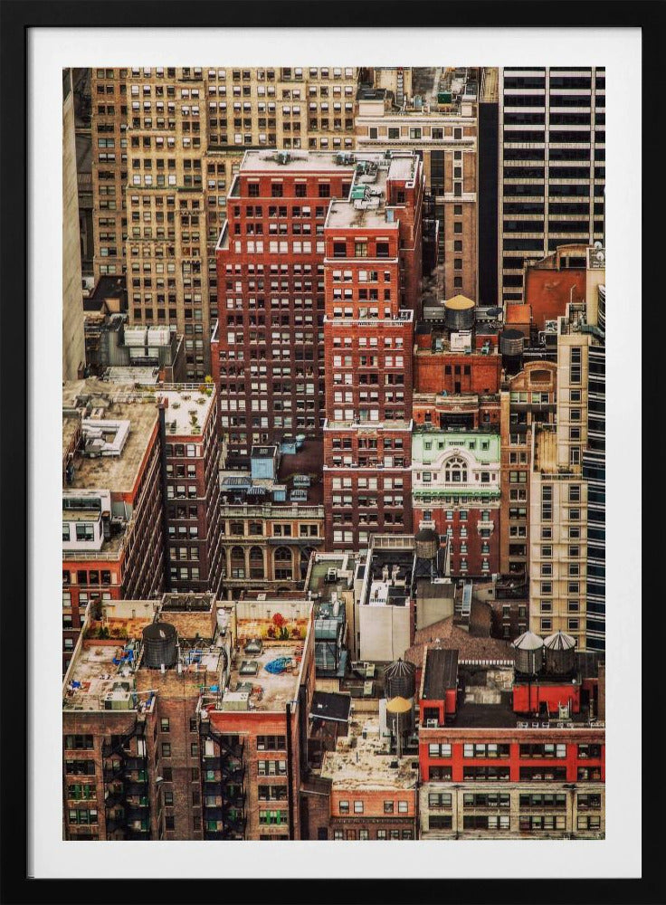 A high-angle, telephoto view of a dense cluster of New York City buildings, featuring a mix of red and brown brick architecture, with numerous windows creating a geometric pattern and several classic wooden water towers perched on the rooftops. Print