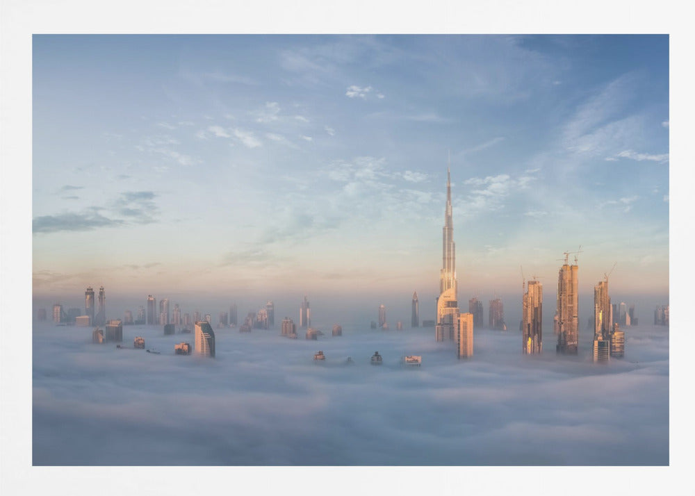 A framed photograph of the Dubai skyline, with the Burj Khalifa and other skyscrapers piercing through a thick blanket of low-lying clouds or fog. The scene is bathed in the warm, golden light of sunrise or sunset against a pale blue sky. Poster