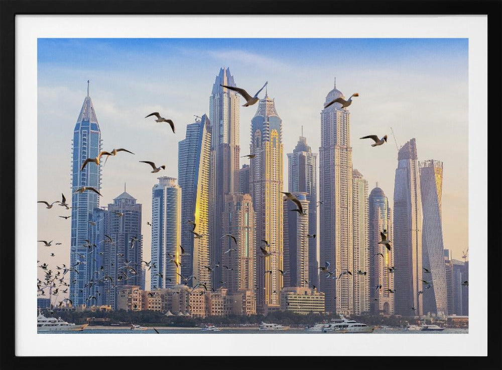 A framed artwork of the Dubai city skyline, featuring modern skyscrapers bathed in the golden light of sunset. A flock of seagulls flies in the foreground above the water, where several yachts are docked. Artwork