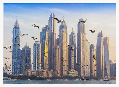 A framed artwork of the Dubai city skyline, featuring modern skyscrapers bathed in the golden light of sunset. A flock of seagulls flies in the foreground above the water, where several yachts are docked. Artwork