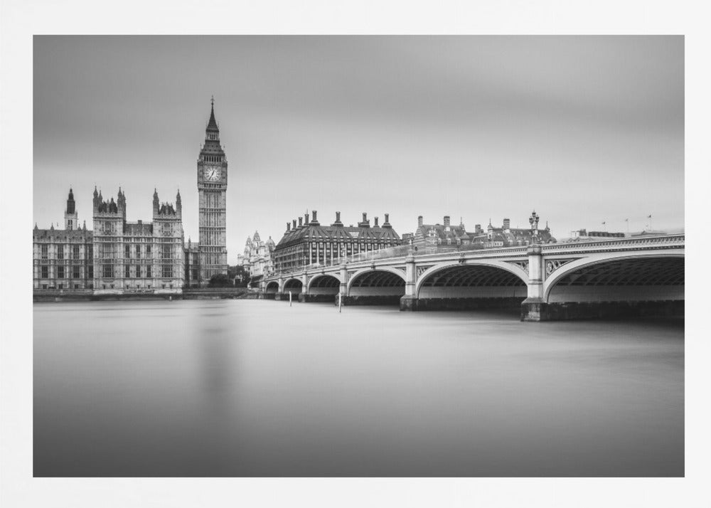 A black and white long-exposure photograph of the Elizabeth Tower (Big Ben) and the Houses of Parliament in London, viewed from across the River Thames. Westminster Bridge stretches across the frame over the smooth, milky water. The image is presented in a silver frame. Artwork