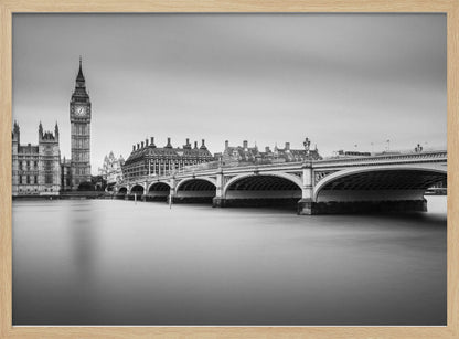 A black and white long-exposure photograph of the Elizabeth Tower (Big Ben) and the Houses of Parliament in London, viewed from across the River Thames. Westminster Bridge stretches across the frame over the smooth, milky water. The image is presented in a silver frame. Artwork