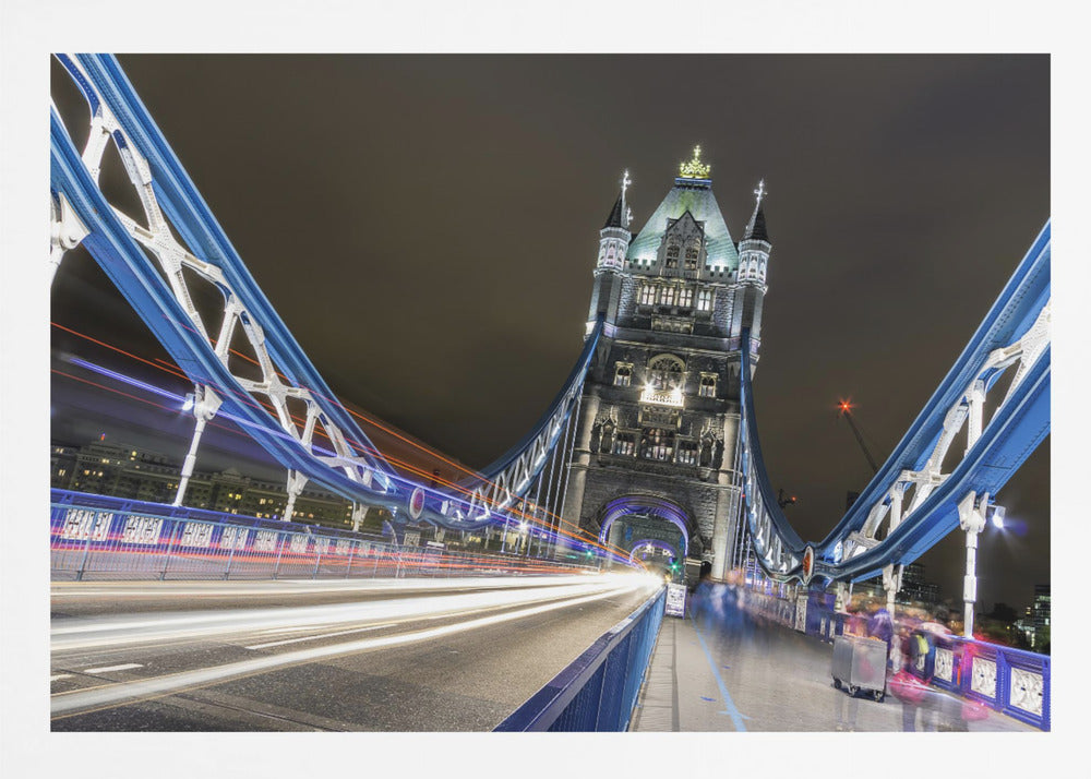 A dramatic, long-exposure night photograph from the deck of London's Tower Bridge, showing vibrant blue support structures curving towards an illuminated stone tower against a dark sky, with bright streaks of light from traffic. Wall Art