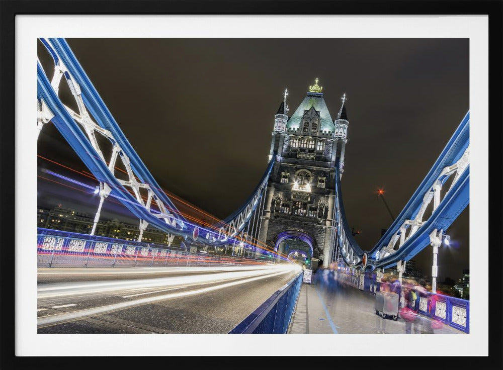 A dramatic, long-exposure night photograph from the deck of London's Tower Bridge, showing vibrant blue support structures curving towards an illuminated stone tower against a dark sky, with bright streaks of light from traffic. Wall Art