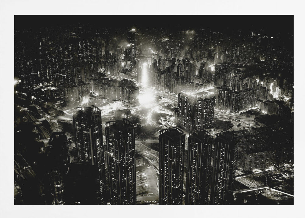 A framed black and white aerial photograph of a dense city at night. The high-angle view captures countless illuminated skyscrapers and winding highways, creating a dramatic and bustling urban landscape. Print