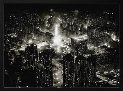 A framed black and white aerial photograph of a dense city at night. The high-angle view captures countless illuminated skyscrapers and winding highways, creating a dramatic and bustling urban landscape. Print