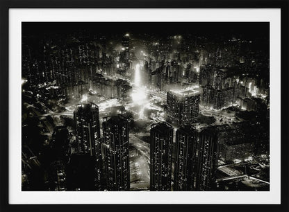 A framed black and white aerial photograph of a dense city at night. The high-angle view captures countless illuminated skyscrapers and winding highways, creating a dramatic and bustling urban landscape. Print