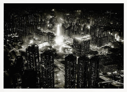 A framed black and white aerial photograph of a dense city at night. The high-angle view captures countless illuminated skyscrapers and winding highways, creating a dramatic and bustling urban landscape. Print