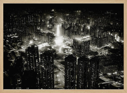 A framed black and white aerial photograph of a dense city at night. The high-angle view captures countless illuminated skyscrapers and winding highways, creating a dramatic and bustling urban landscape. Print