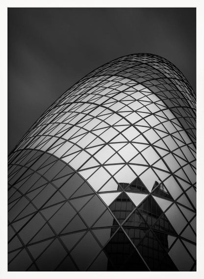 A framed, low-angle, black and white photograph of the curved, glass-paneled facade of a modern skyscraper, creating a dynamic pattern of reflective diamonds against a dark, moody sky. Artwork