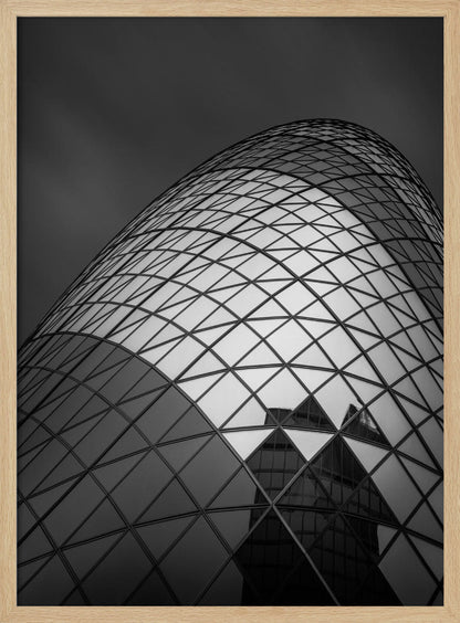 A framed, low-angle, black and white photograph of the curved, glass-paneled facade of a modern skyscraper, creating a dynamic pattern of reflective diamonds against a dark, moody sky. Artwork