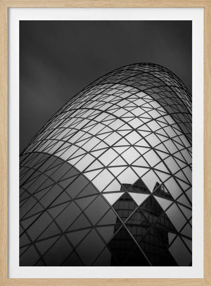 A framed, low-angle, black and white photograph of the curved, glass-paneled facade of a modern skyscraper, creating a dynamic pattern of reflective diamonds against a dark, moody sky. Artwork