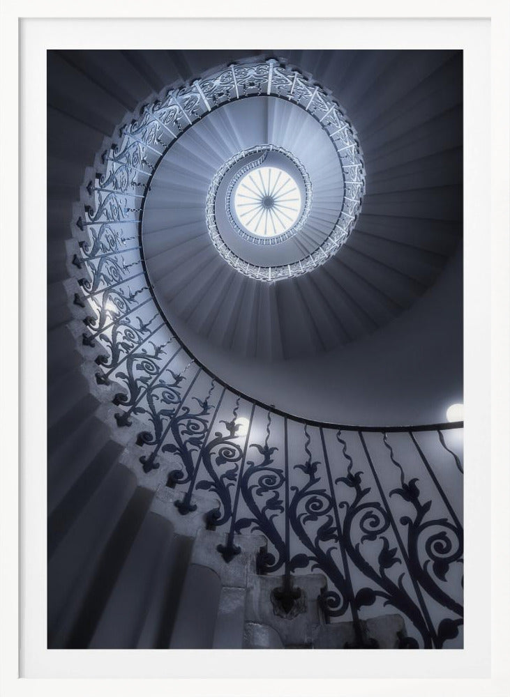A dramatic low-angle view looking up a majestic spiral staircase, its ornate black wrought iron railings creating a dark, intricate pattern against the cool-toned white steps that wind towards a circular skylight at the apex. Decor