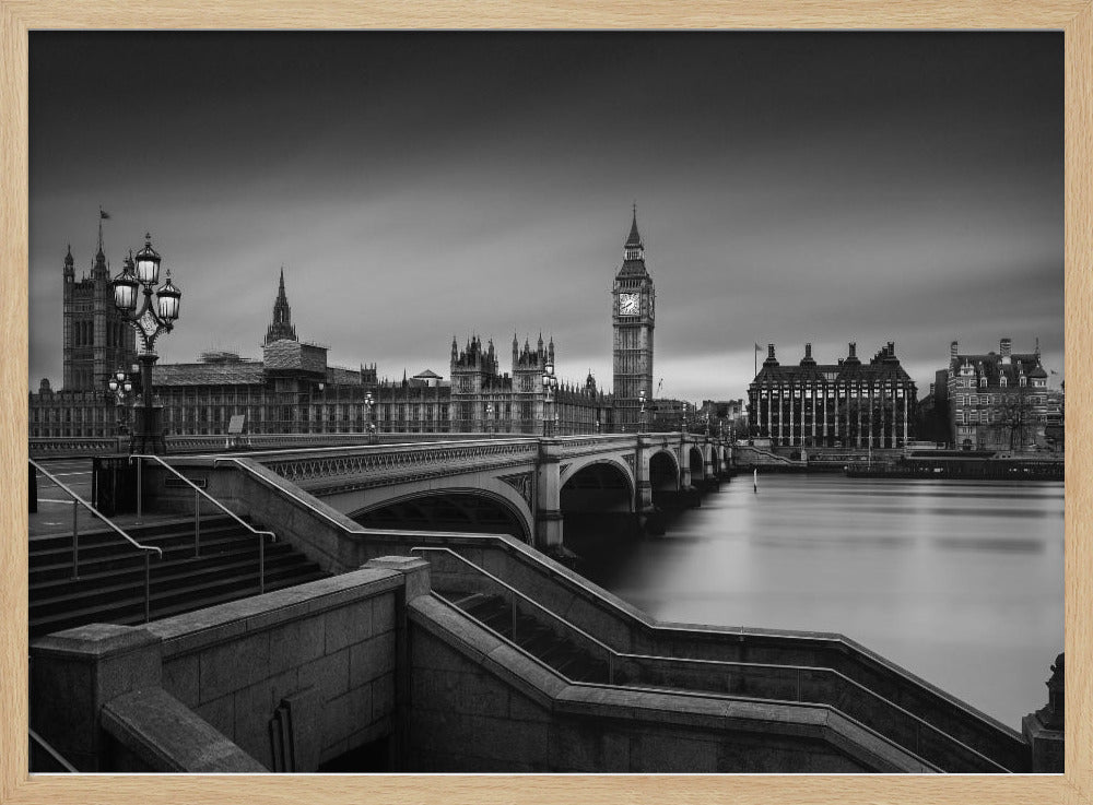 A framed, black and white, long-exposure photograph of the London skyline featuring the Houses of Parliament and the Big Ben clock tower across the River Thames. In the foreground, stone steps lead down towards Westminster Bridge, and the water of the river is smooth and reflective under a dark, cloudy sky. Print