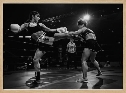 A dramatic black and white action photograph of two female kickboxers in a ring. One fighter, airborne, executes a high kick that connects with the other fighter's gloves, who is bracing for the impact. A referee stands in the background under bright arena lights. Poster