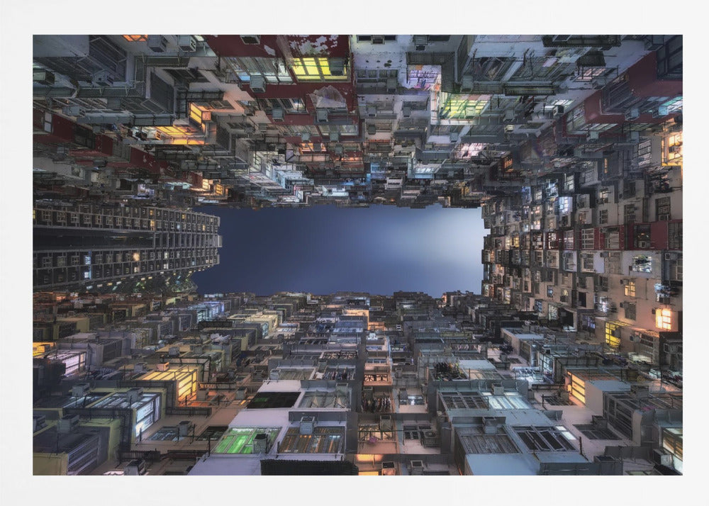 A striking low-angle photograph looking up from a narrow courtyard at the night sky, completely framed by towering, densely packed, and weathered apartment buildings with glowing windows, creating a sense of urban enclosure. Decor