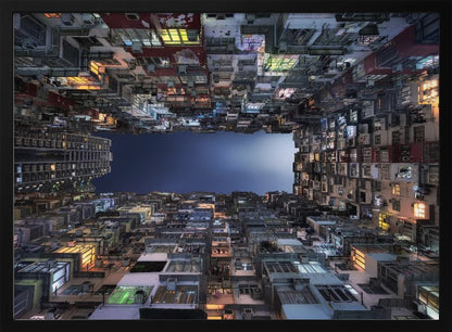 A striking low-angle photograph looking up from a narrow courtyard at the night sky, completely framed by towering, densely packed, and weathered apartment buildings with glowing windows, creating a sense of urban enclosure. Decor