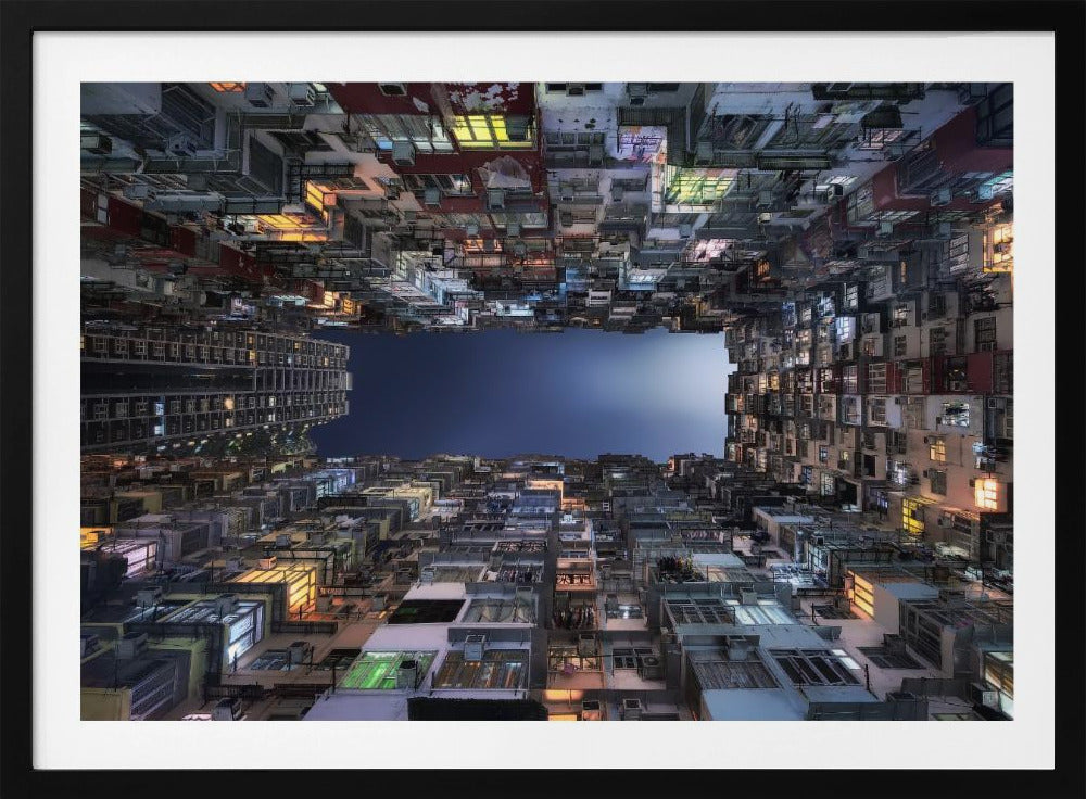 A striking low-angle photograph looking up from a narrow courtyard at the night sky, completely framed by towering, densely packed, and weathered apartment buildings with glowing windows, creating a sense of urban enclosure. Decor
