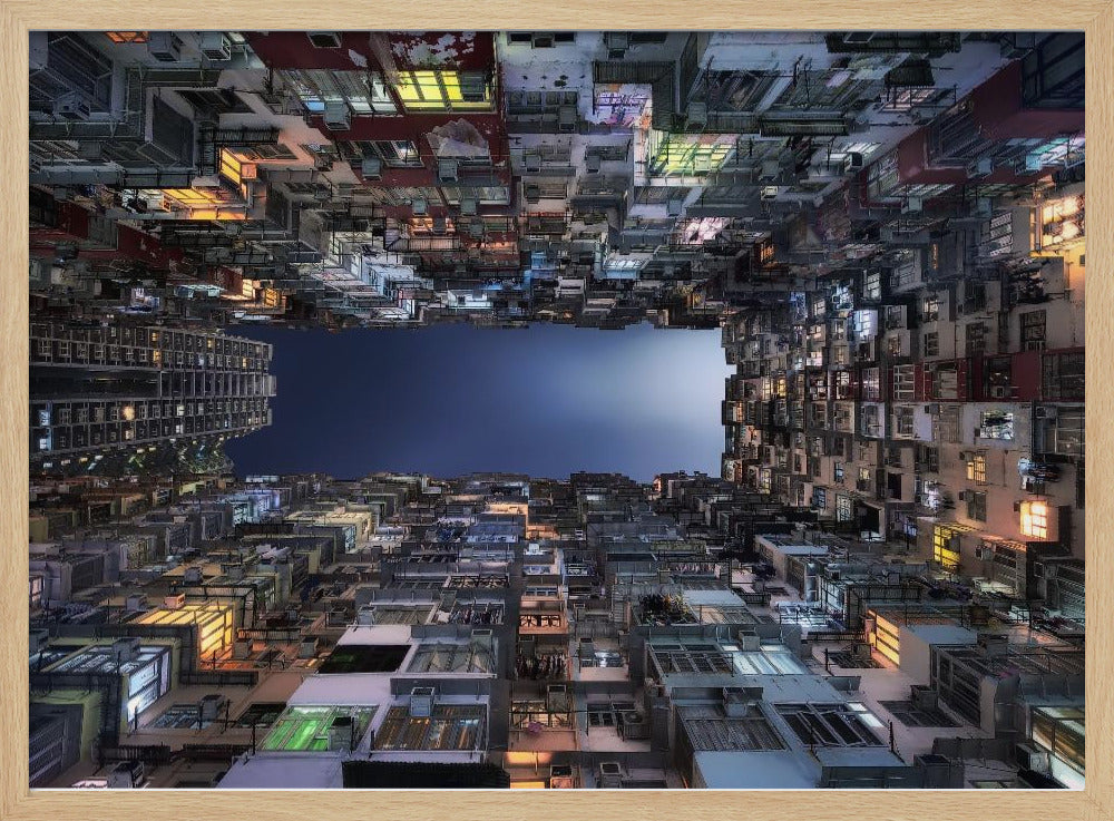 A striking low-angle photograph looking up from a narrow courtyard at the night sky, completely framed by towering, densely packed, and weathered apartment buildings with glowing windows, creating a sense of urban enclosure. Decor