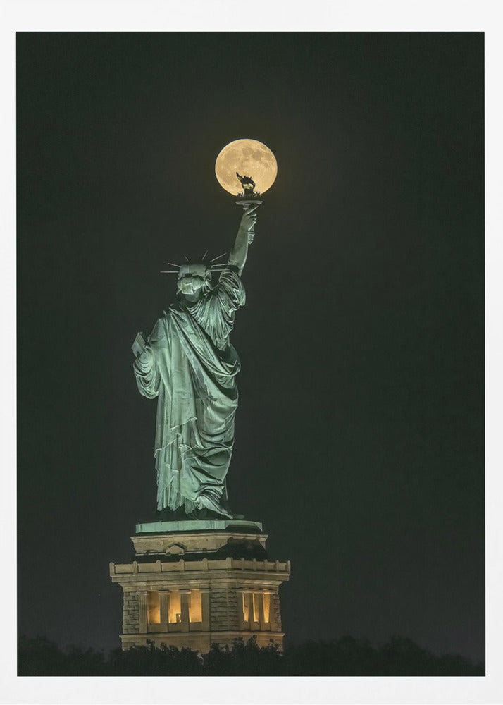 A striking night photograph of the Statue of Liberty, where a large, full yellow moon is perfectly aligned behind the torch, creating the illusion that the statue is holding up the moon. Artwork