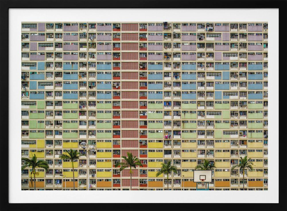 A symmetrical, frontal photograph of the colorful Choi Hung Estate in Hong Kong, featuring a massive grid of apartments with balconies painted in a rainbow of pastel colors including purple, blue, green, yellow, and orange. Palm trees and a basketball court are visible at the base of the building, which is enclosed in a silver frame. Wall Art