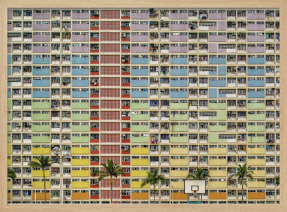 A symmetrical, frontal photograph of the colorful Choi Hung Estate in Hong Kong, featuring a massive grid of apartments with balconies painted in a rainbow of pastel colors including purple, blue, green, yellow, and orange. Palm trees and a basketball court are visible at the base of the building, which is enclosed in a silver frame. Wall Art