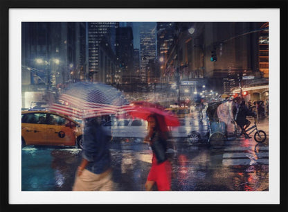 An artistic motion-blur photograph of a rainy night on East 42nd Street in New York City. Pedestrians with umbrellas, one with an American flag design and another bright red, cross the wet street as city lights and a yellow taxi reflect on the pavement, creating a vibrant, impressionistic scene within a silver frame. Decor