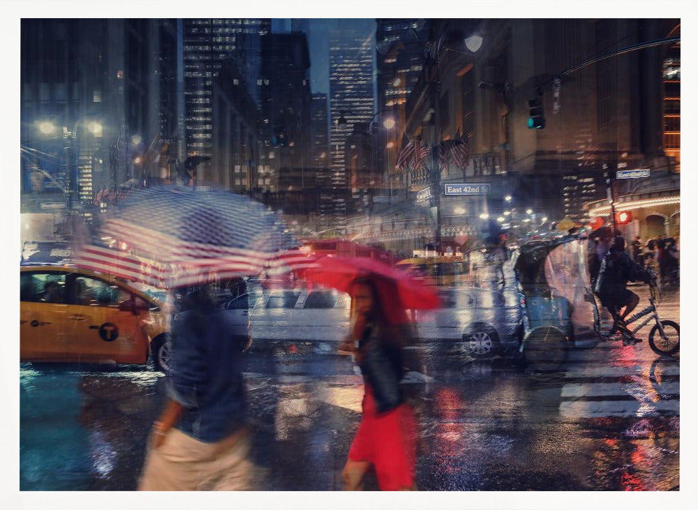 An artistic motion-blur photograph of a rainy night on East 42nd Street in New York City. Pedestrians with umbrellas, one with an American flag design and another bright red, cross the wet street as city lights and a yellow taxi reflect on the pavement, creating a vibrant, impressionistic scene within a silver frame. Decor