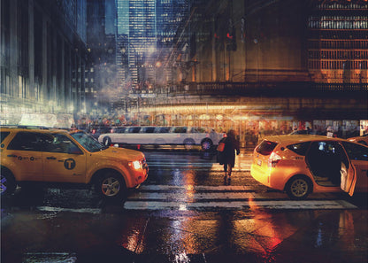 A cinematic night photograph of a busy, wet city street, likely New York, with yellow taxis in the foreground and a white stretch limousine in the background. A pedestrian crosses the street as the city lights reflect off the wet pavement, with illuminated skyscrapers towering above. Decor