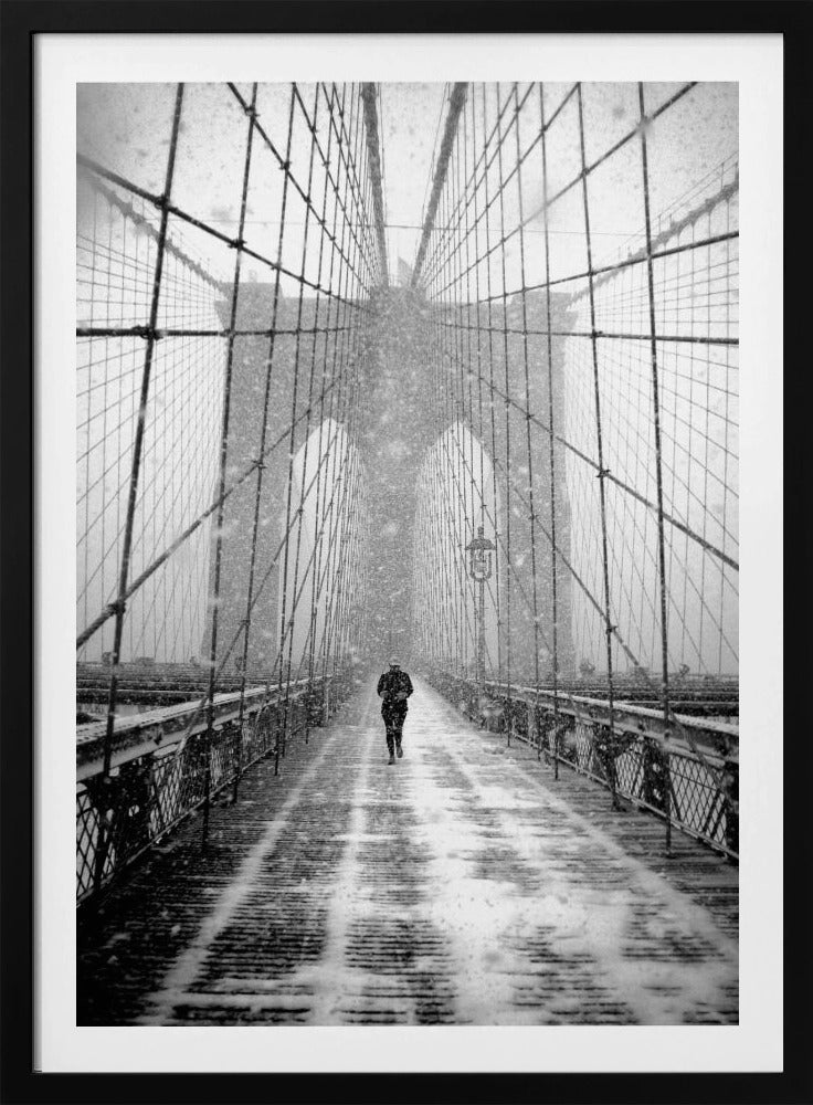 A vertical, black and white photograph of a solitary person walking along the Brooklyn Bridge during a heavy snowstorm. The iconic cables and towers of the bridge create a strong sense of perspective, drawing the eye towards the distant, hazy towers while snow falls all around. Artwork