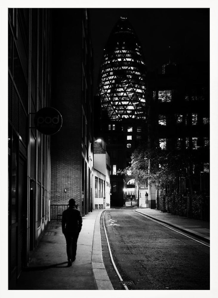 A moody black and white photograph of a person walking away down a narrow, deserted city street at night. In the background, the iconic Gherkin building in London is brightly lit against the dark sky. Wall Art
