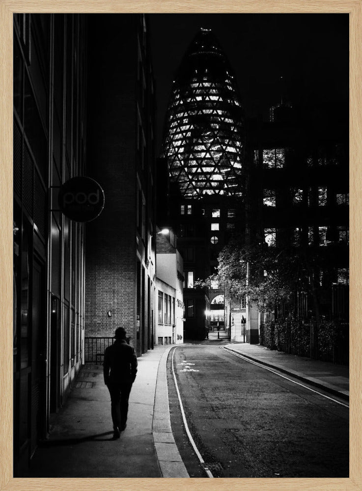 A moody black and white photograph of a person walking away down a narrow, deserted city street at night. In the background, the iconic Gherkin building in London is brightly lit against the dark sky. Wall Art