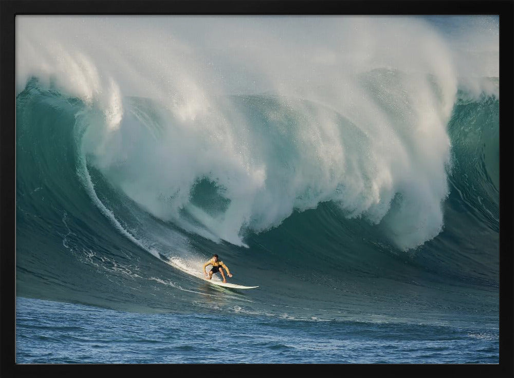 A lone surfer in a yellow shirt rides down the face of an enormous, powerful ocean wave as it crests into white foam, viewed within a silver picture frame. Wall Art