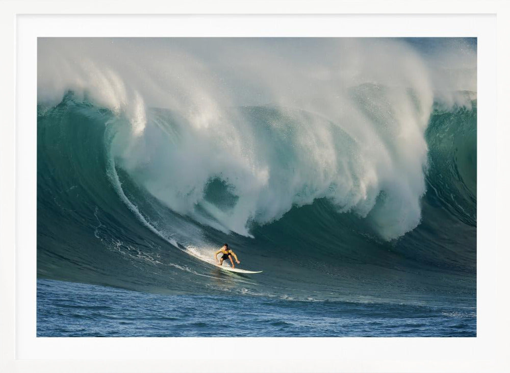A lone surfer in a yellow shirt rides down the face of an enormous, powerful ocean wave as it crests into white foam, viewed within a silver picture frame. Wall Art