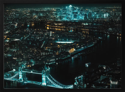 A framed aerial photograph of London at night, featuring the iconic Tower Bridge illuminated in bright teal in the foreground and the glowing skyscrapers of Canary Wharf across the River Thames in the background. Artwork