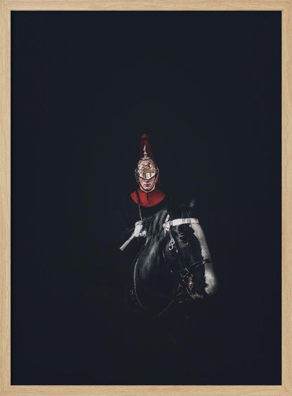 A dramatic portrait of a British Royal Guard on a black horse, emerging from a completely black background. The guard is wearing a traditional uniform with a red collar and a shiny gold helmet with a red plume. Poster