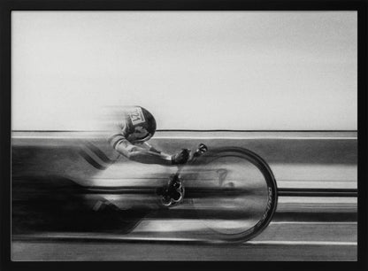 A black and white photograph captured with motion blur, showing a cyclist in an aerodynamic position racing at high speed. The background is blurred into horizontal lines, emphasizing the velocity. The image is enclosed in a silver frame. Wall Art