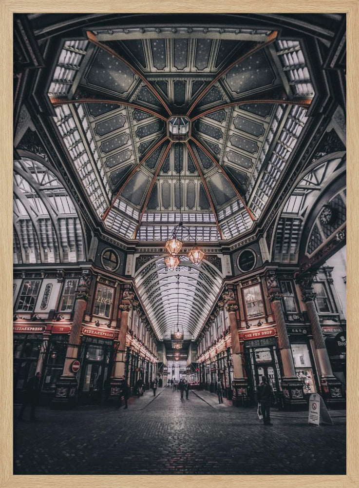A wide-angle, symmetrical photograph looking down the center of an ornate Victorian covered market, Leadenhall Market. The focus is on the elaborate, arched glass and ironwork ceiling which is decorated in dark blue with gold stars. Below, a cobblestone path is lined with traditional shops with glowing lights, and a few people can be seen walking in the distance. The image has a moody, high-contrast aesthetic. Wall Art