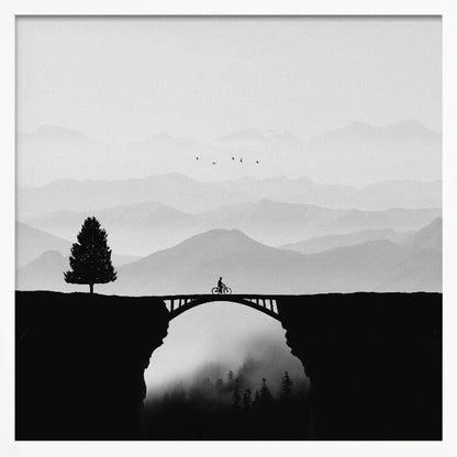 A minimalist black and white artwork featuring the silhouette of a cyclist crossing a high arched bridge between two cliffs. A lone tree stands on one cliff, while layers of misty mountains fill the background, creating a sense of depth and solitude. Poster