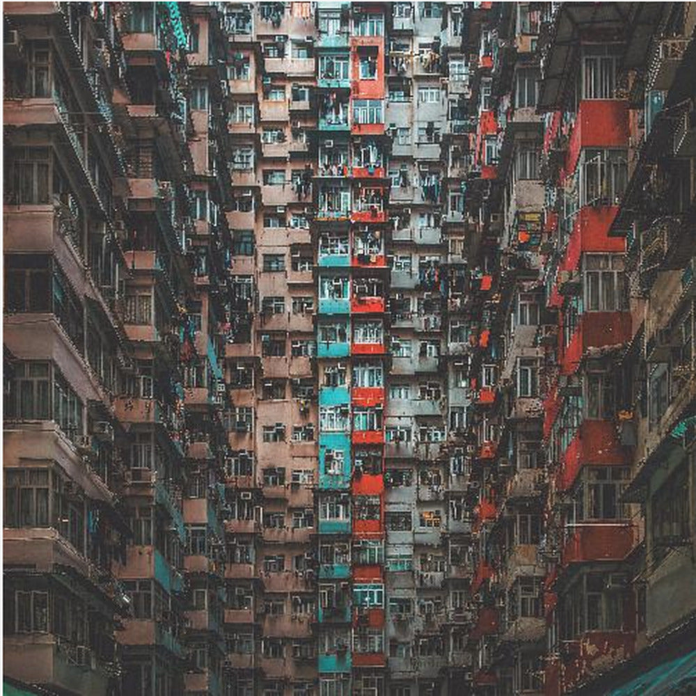 A framed, low-angle photograph looking up at densely packed, weathered apartment buildings that create a canyon-like view, with some facades painted in vibrant red and teal. Wall Art