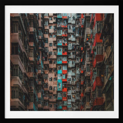 A framed, low-angle photograph looking up at densely packed, weathered apartment buildings that create a canyon-like view, with some facades painted in vibrant red and teal. Wall Art