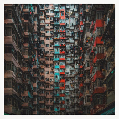 A framed, low-angle photograph looking up at densely packed, weathered apartment buildings that create a canyon-like view, with some facades painted in vibrant red and teal. Wall Art