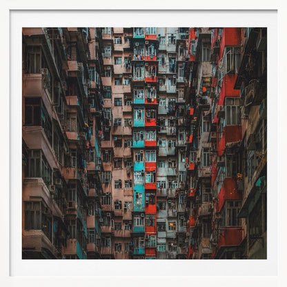 A framed, low-angle photograph looking up at densely packed, weathered apartment buildings that create a canyon-like view, with some facades painted in vibrant red and teal. Wall Art