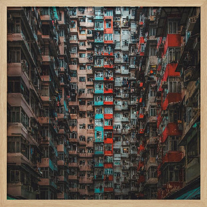 A framed, low-angle photograph looking up at densely packed, weathered apartment buildings that create a canyon-like view, with some facades painted in vibrant red and teal. Wall Art